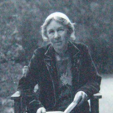 Black and white photograph of a female.  Figure seated in a chair reading a book. 